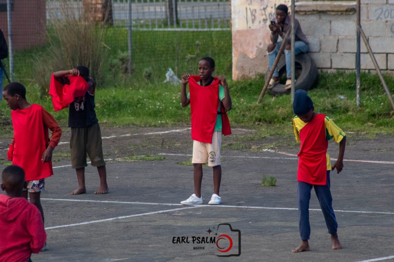 Young players pulling on red bibs before a game on an outdoor court