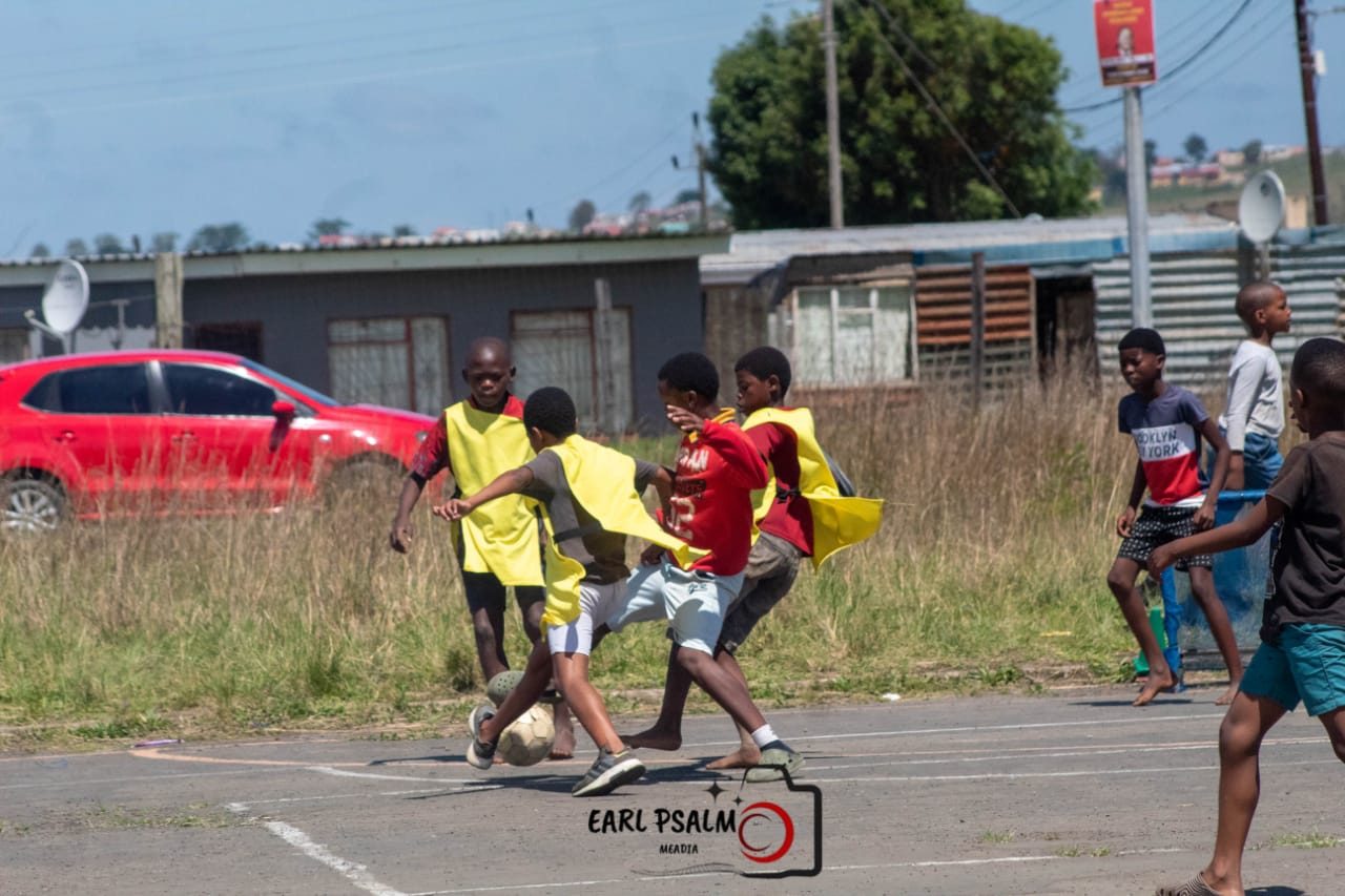 Two boys going for the ball during a game on the edge of a neighbourhood court