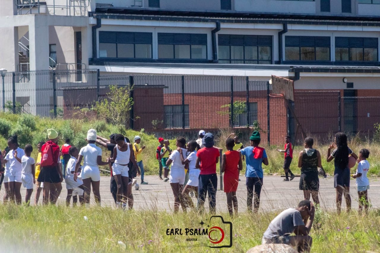 Young people gathered around an outdoor court in Dimbaza before a game