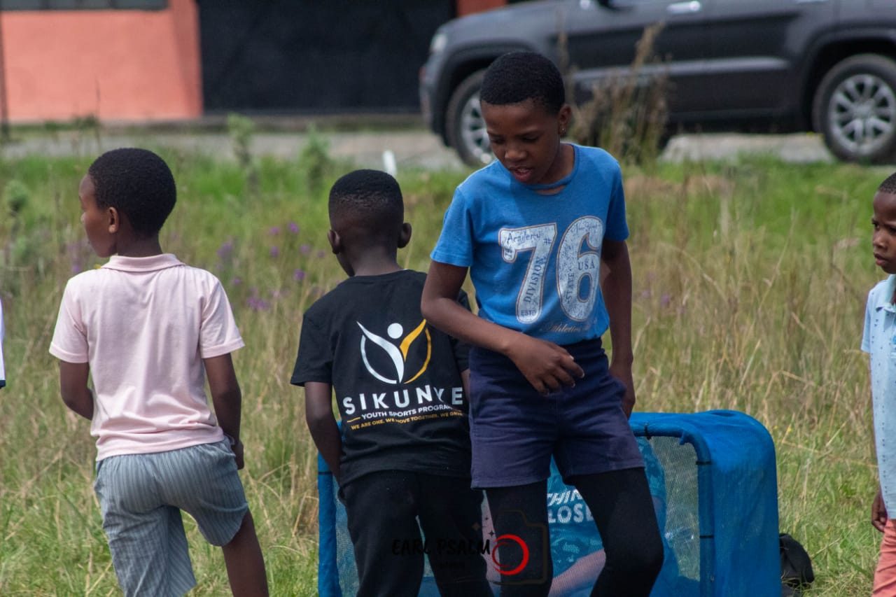 Young players gathered around a portable goal on a grass field