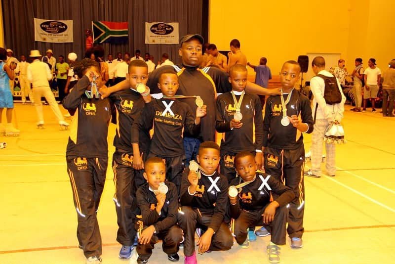 Young Dimbaza skaters and their coach showing their medals