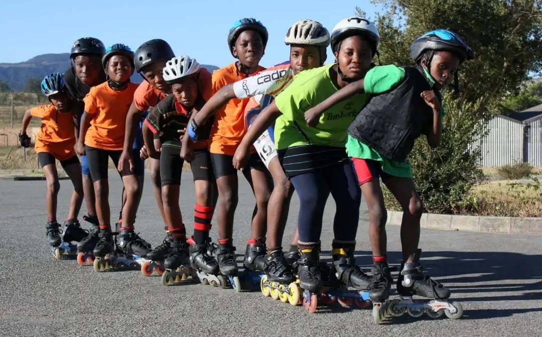 Young skaters wearing helmets lined up together on the road